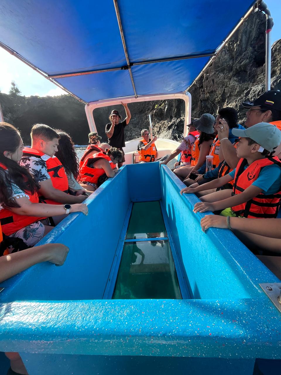 People standing around the floor window of the boat